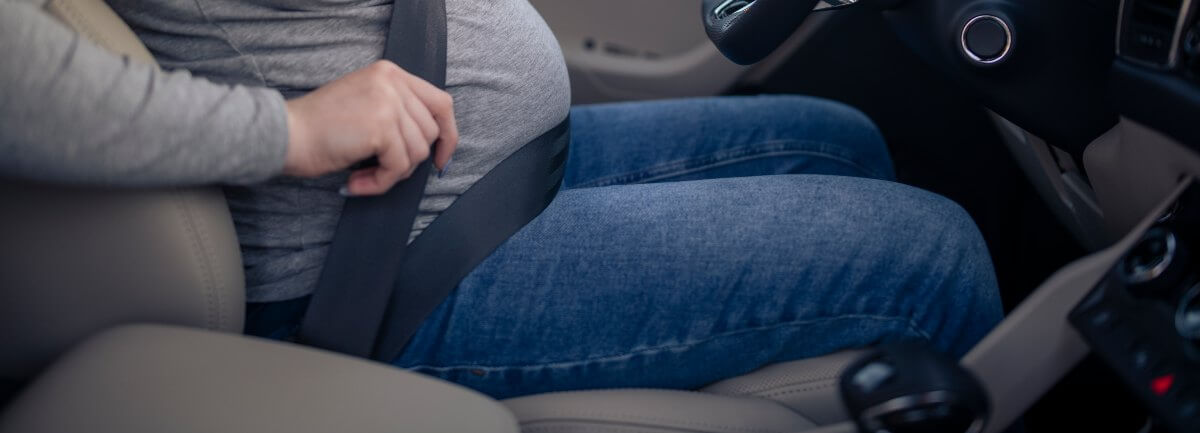 pregnant woman putting on seat belt