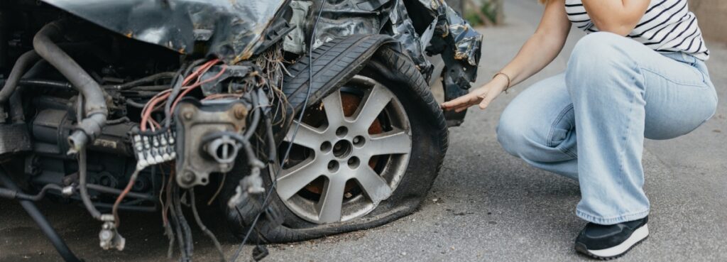 A woman examining the damages to her car.