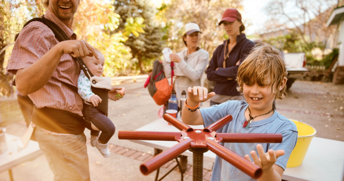 A boy making apple cider outside.