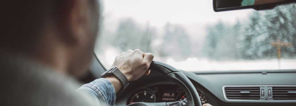 Man in a car driving through winter weather