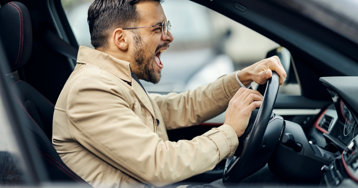 A man yelling in the car while driving on the road.