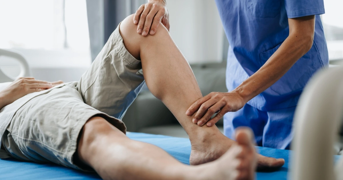 Medical professional stretching patient leg during treatment.