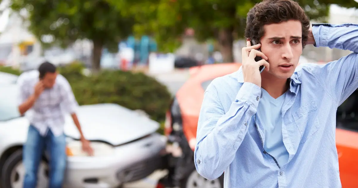 Young male driver on phone after a car crash