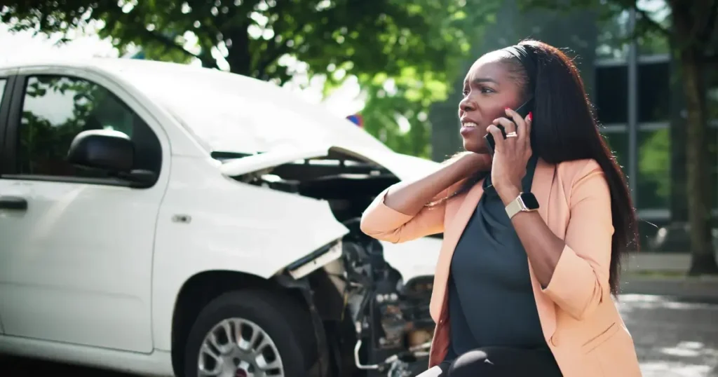 young black woman on phone in front of her crashed car